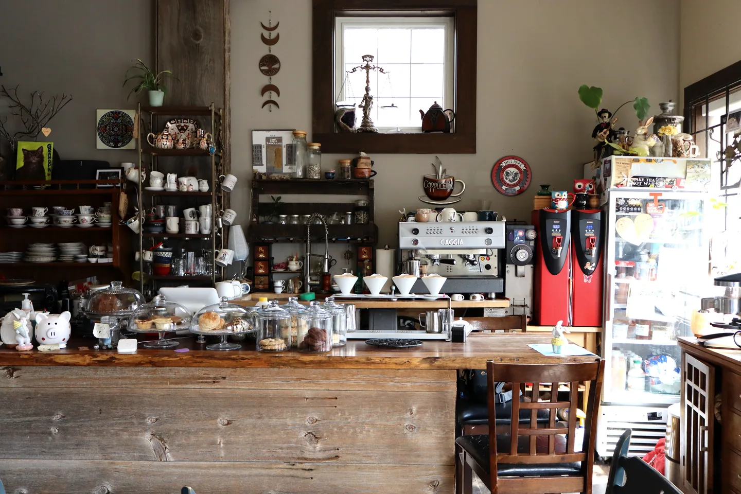 The wooden counter, tea shelves and collected cups inside Lukaya Cafe