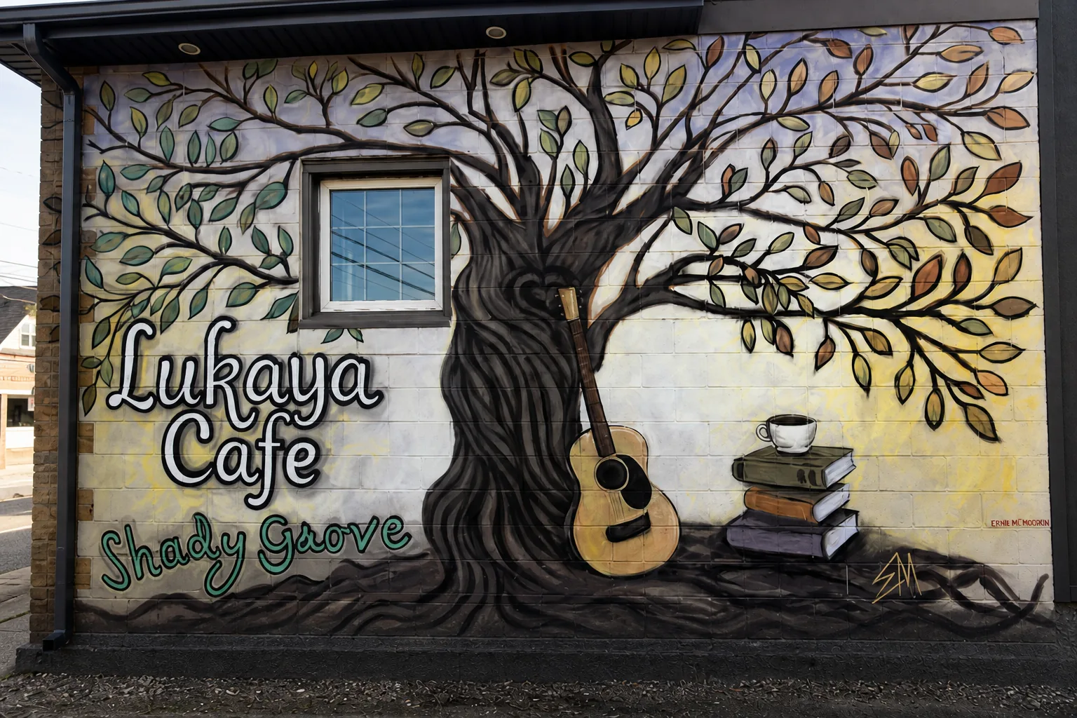 A cup, books, guitar and tree in Lukaya Cafe's cleaned mural photograph